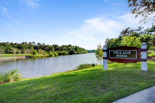 community / neighborhood sign featuring a lawn and a water view