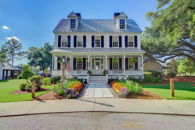 view of front facade featuring a front lawn, covered porch, and metal roof