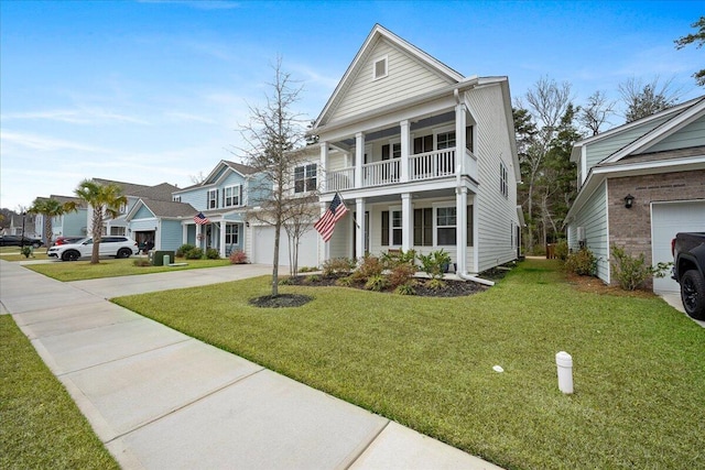 greek revival house with a garage, a front yard, a balcony, and driveway