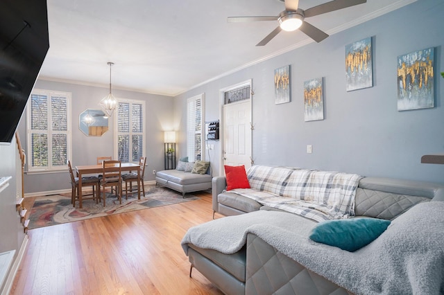 living room with hardwood / wood-style floors, crown molding, and ceiling fan with notable chandelier