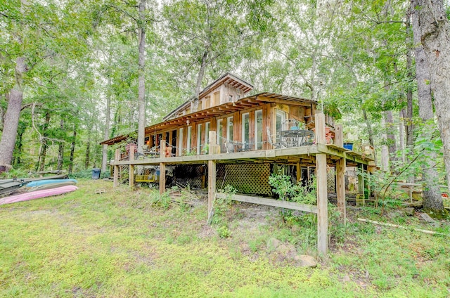 rear view of house featuring a wooden deck and a yard