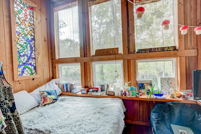 bedroom with multiple windows and wooden walls