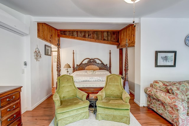 bedroom featuring an AC wall unit, beamed ceiling, and light wood-type flooring