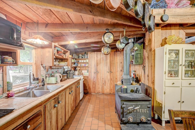 kitchen with wooden walls, sink, a wood stove, white gas range oven, and beam ceiling