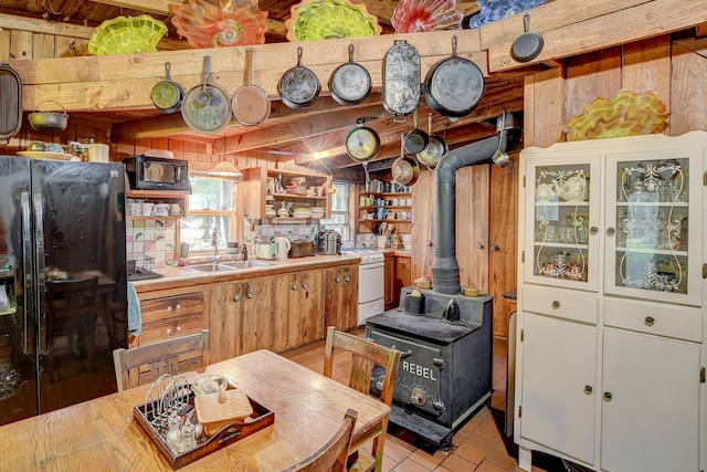 kitchen featuring white cabinetry, sink, black appliances, and a wood stove