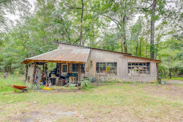 rear view of house featuring a garage, an outdoor structure, and a lawn