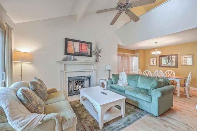 living room with ceiling fan with notable chandelier, vaulted ceiling with beams, and light hardwood / wood-style flooring