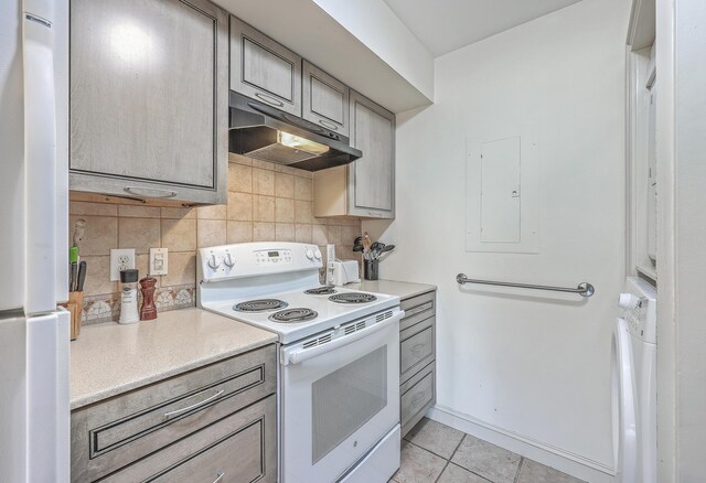 kitchen featuring decorative backsplash, light tile patterned floors, white appliances, and electric panel