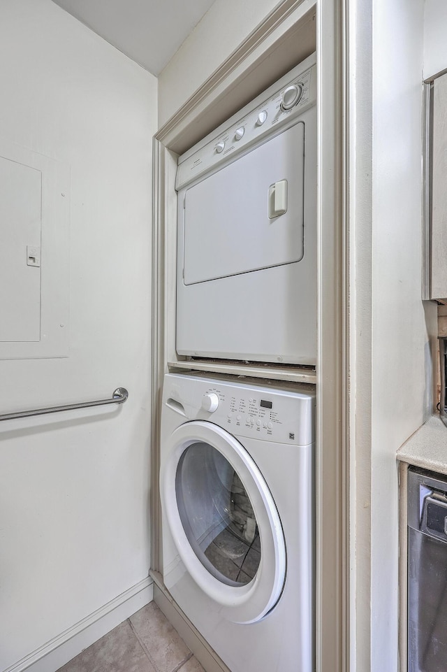 laundry area featuring light tile patterned flooring, electric panel, and stacked washer / drying machine