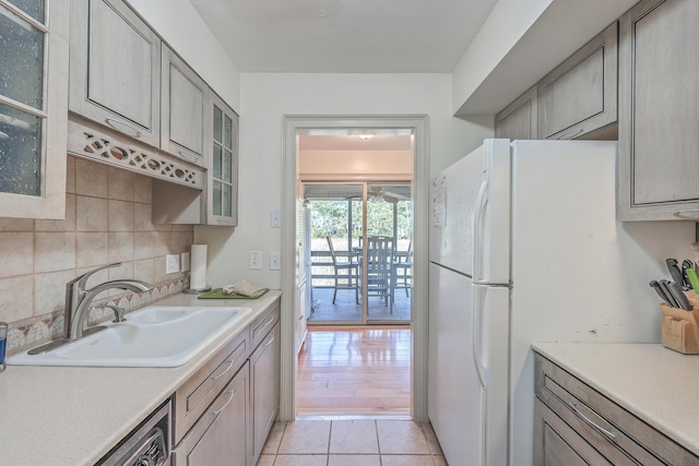 kitchen featuring dishwasher, sink, backsplash, light tile patterned flooring, and gray cabinets