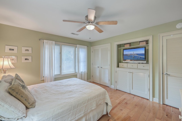 bedroom featuring multiple closets, light hardwood / wood-style floors, and ceiling fan