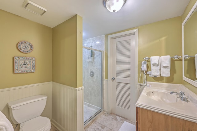 bathroom featuring toilet, a shower with shower door, and vanity