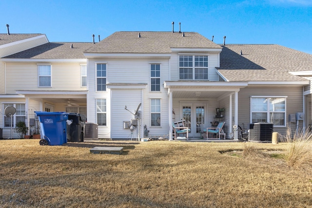 rear view of house with central AC unit, french doors, and a lawn