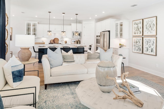 living room with light wood finished floors, baseboards, visible vents, and recessed lighting