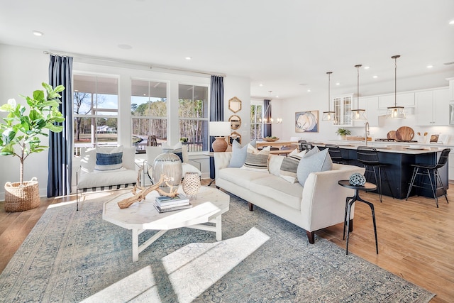 living room with light wood-type flooring, an inviting chandelier, and recessed lighting