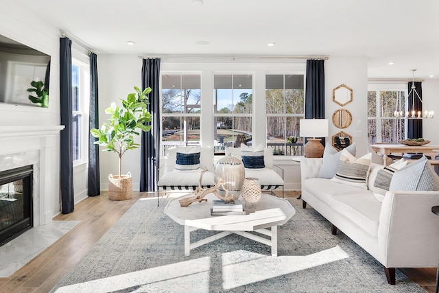 living area featuring a high end fireplace, a notable chandelier, plenty of natural light, and wood finished floors