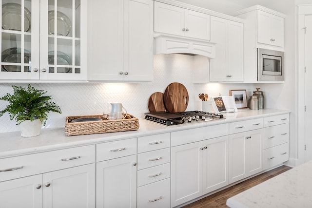 kitchen with white cabinets, glass insert cabinets, stainless steel appliances, and light stone counters