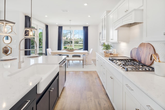 kitchen featuring hanging light fixtures, appliances with stainless steel finishes, light stone countertops, and white cabinets