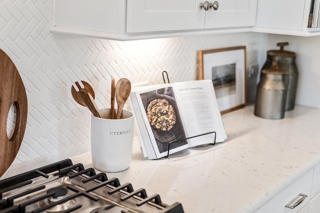 room details featuring light stone counters, white cabinets, and tasteful backsplash