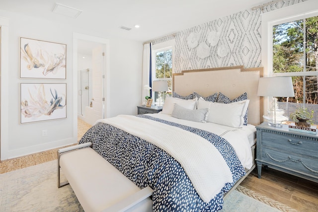 bedroom with baseboards, connected bathroom, light wood-style flooring, and wallpapered walls