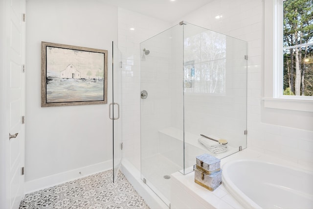 bathroom with a stall shower, baseboards, a bath, and tile patterned floors