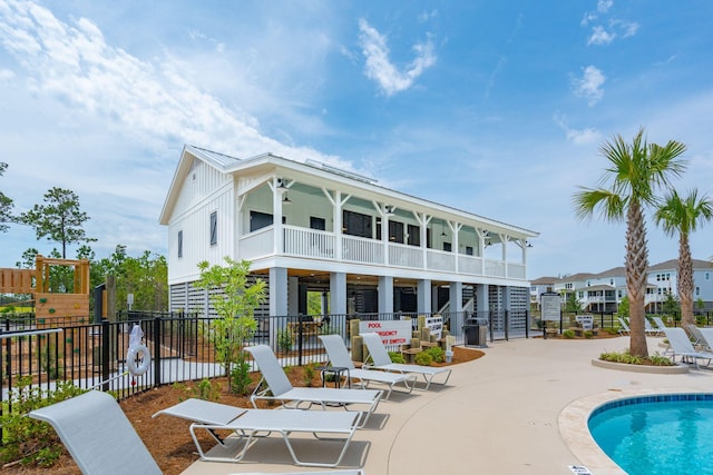 rear view of house featuring a ceiling fan, a community pool, fence, a patio area, and board and batten siding