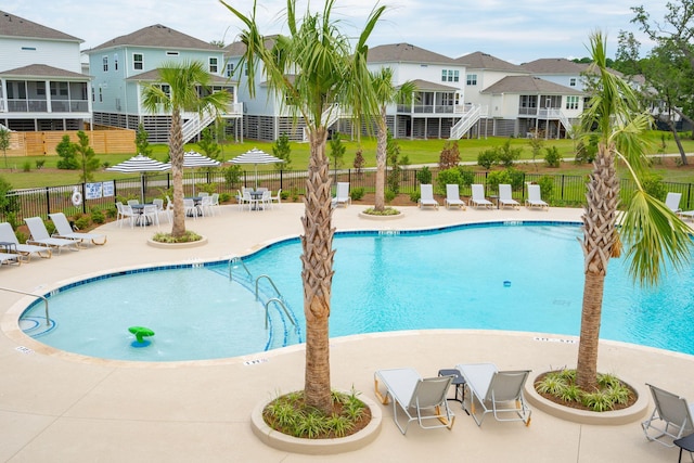 community pool with a patio area, a residential view, and fence