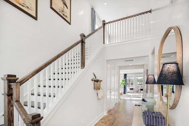 interior space with stairway, visible vents, a towering ceiling, and wood finished floors