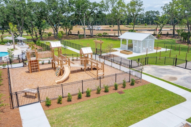 view of community featuring playground community, a yard, and fence