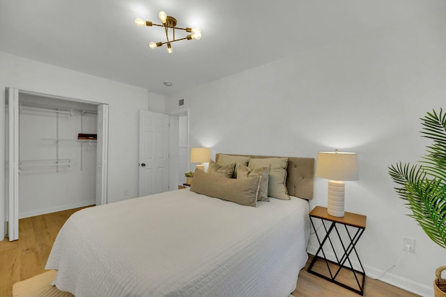 bedroom featuring a closet, a notable chandelier, baseboards, and wood finished floors