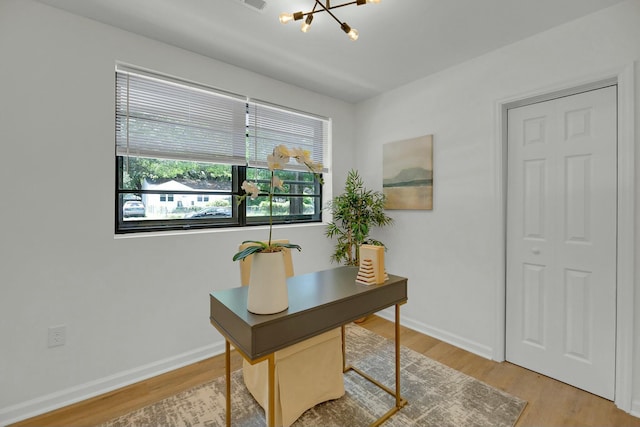 office space featuring light wood-style flooring, baseboards, and a chandelier