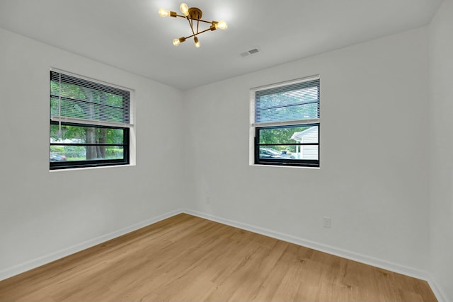 unfurnished room featuring visible vents, baseboards, a chandelier, and light wood finished floors