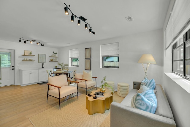 living room featuring light wood finished floors, visible vents, and rail lighting