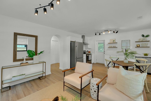 living area featuring baseboards, light wood-type flooring, arched walkways, and visible vents