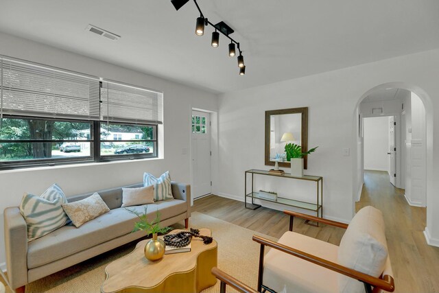 living area featuring wood finished floors, visible vents, arched walkways, and baseboards