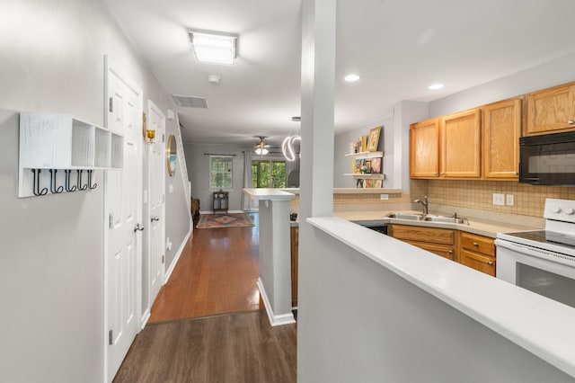 kitchen with white electric range oven, sink, kitchen peninsula, dark hardwood / wood-style flooring, and decorative backsplash