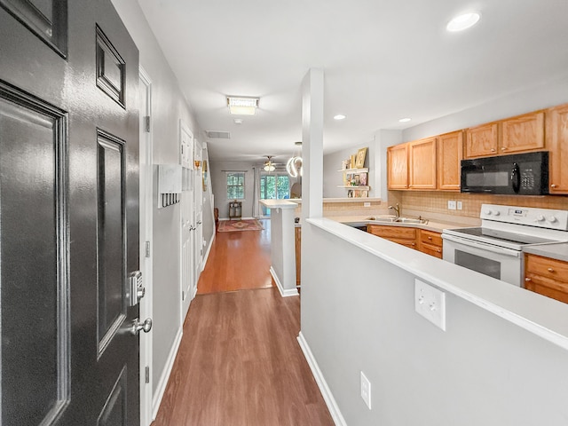 kitchen featuring sink, kitchen peninsula, ceiling fan, white electric range, and dark hardwood / wood-style flooring