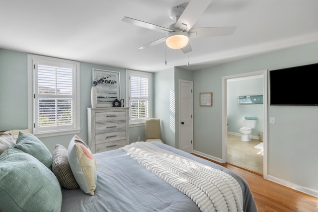 bedroom with ensuite bath, ceiling fan, multiple windows, and light wood-type flooring