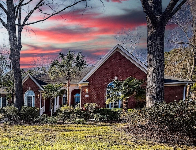 view of front of property featuring a yard and brick siding