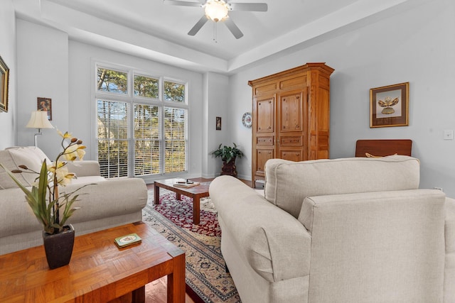 living area featuring baseboards and ceiling fan