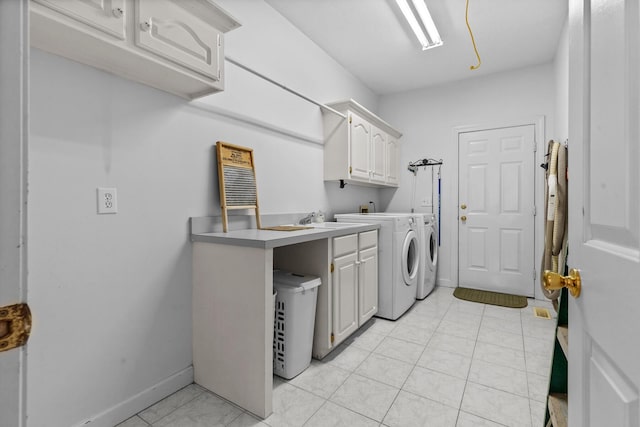 washroom featuring baseboards, light tile patterned flooring, cabinet space, a sink, and washer and clothes dryer