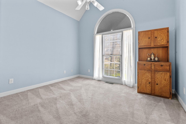 unfurnished room featuring visible vents, ceiling fan, baseboards, light colored carpet, and vaulted ceiling