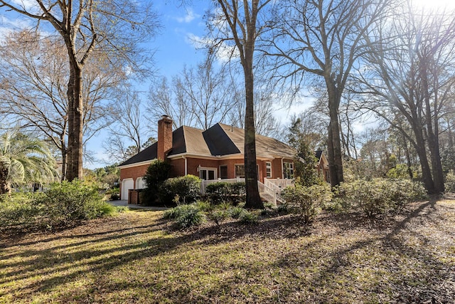 exterior space featuring a garage, brick siding, and a chimney