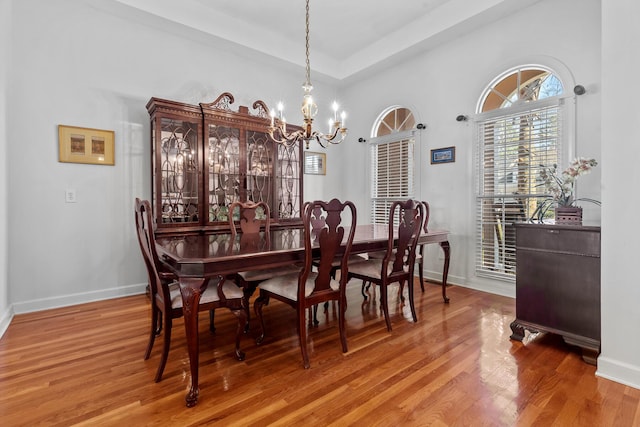 dining space featuring wood finished floors, baseboards, and a chandelier