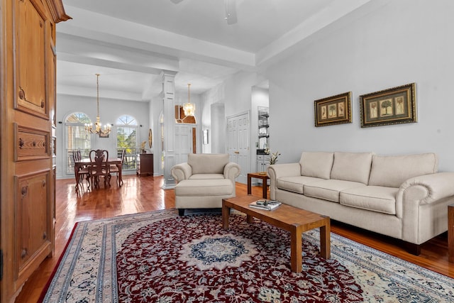 living area with ceiling fan with notable chandelier, wood finished floors, and ornate columns