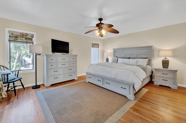 bedroom featuring light wood finished floors, baseboards, and a ceiling fan