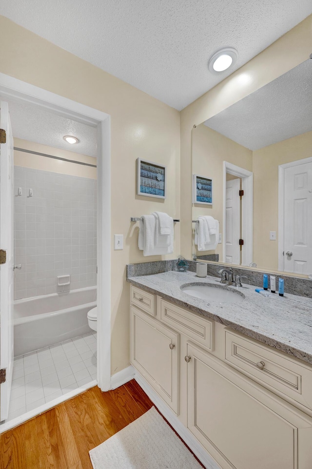 full bathroom with toilet, wood finished floors, bathtub / shower combination, a textured ceiling, and vanity