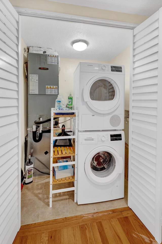 clothes washing area with tile patterned floors and stacked washer and clothes dryer