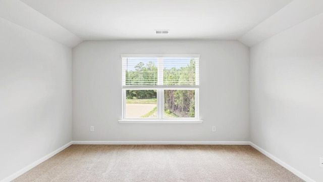 carpeted empty room featuring vaulted ceiling