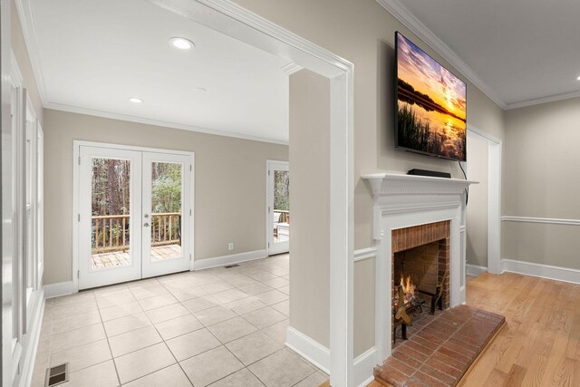 unfurnished living room featuring crown molding, light hardwood / wood-style flooring, french doors, and a fireplace